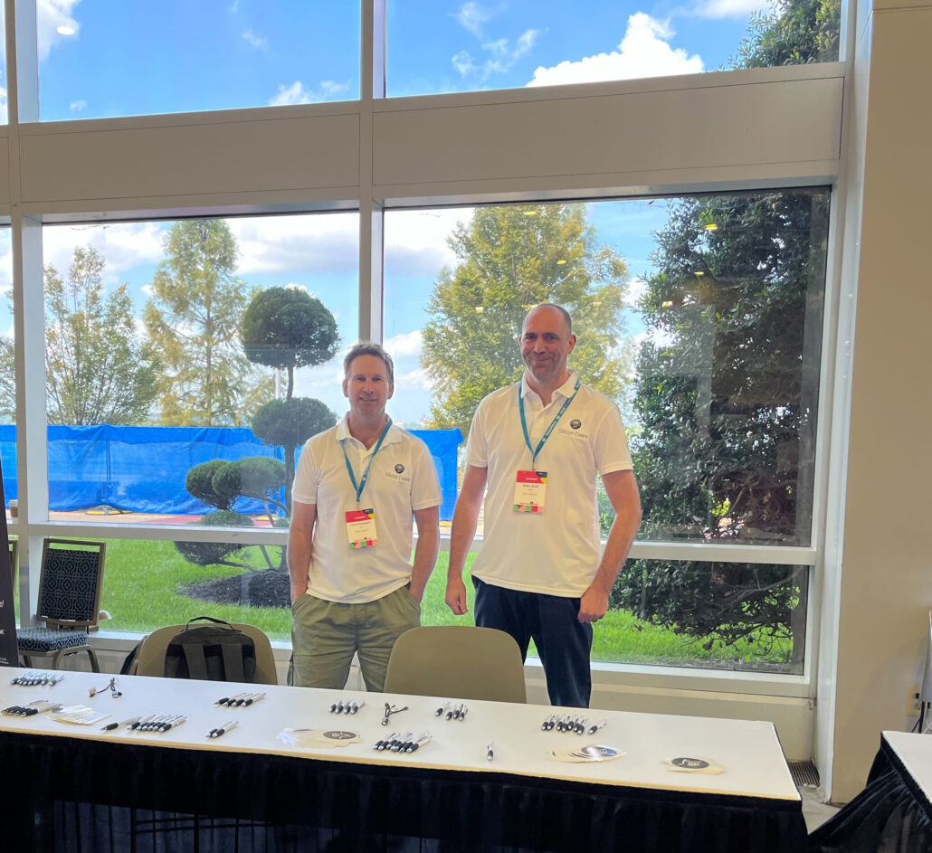 Jonathan Farrington and Robin Scott at WordCamp US 2023 in National Harbor USA, standing behind a Silicon Dales booth. Most of their swag has been taken :)